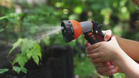 Focus-on-mother-and-daughter-watering-plants-in-garden