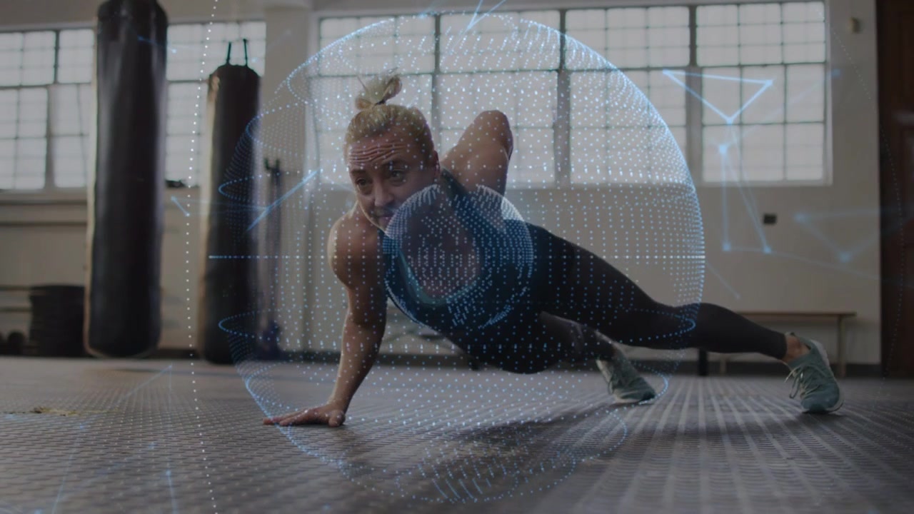 Woman performing one-arm plank in gym, digital sphere appearing initiating torso rotation for core