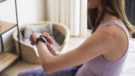 middle-aged caucasian woman checks her fitness tracker at home