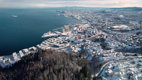 drone aéreo de trondheim en invierno cubierto de nieve a lo largo del río nidelva, noruega