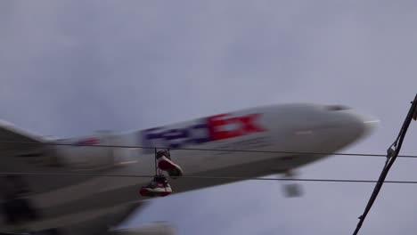 a nice low angle of tennis shoes on a line as a fedex plane lands in southern california