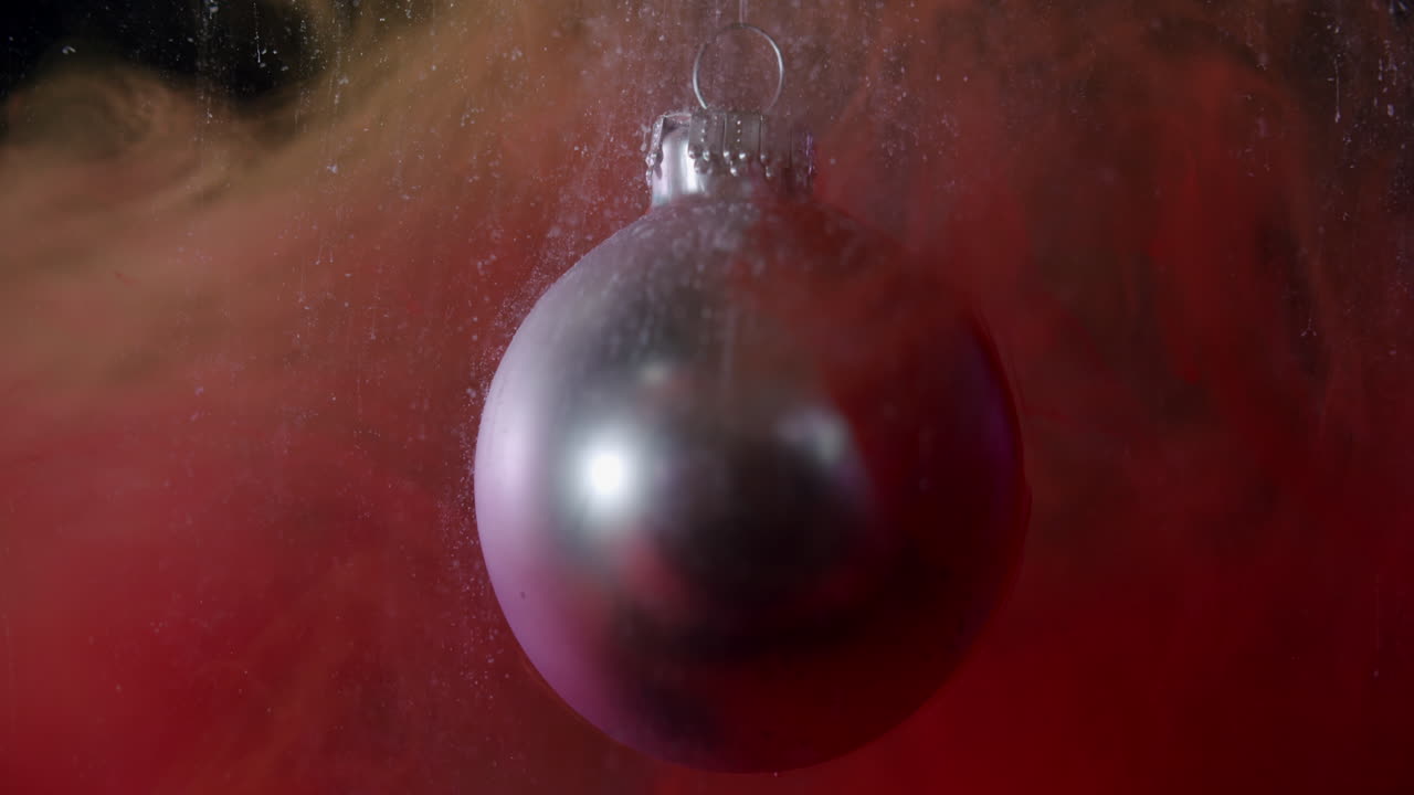 눈처럼 보이는 작은 연기 입자가 있는 매크로 샷 크리스마스 값싼 물건이 슬로우 모션으로 떨어집니다.