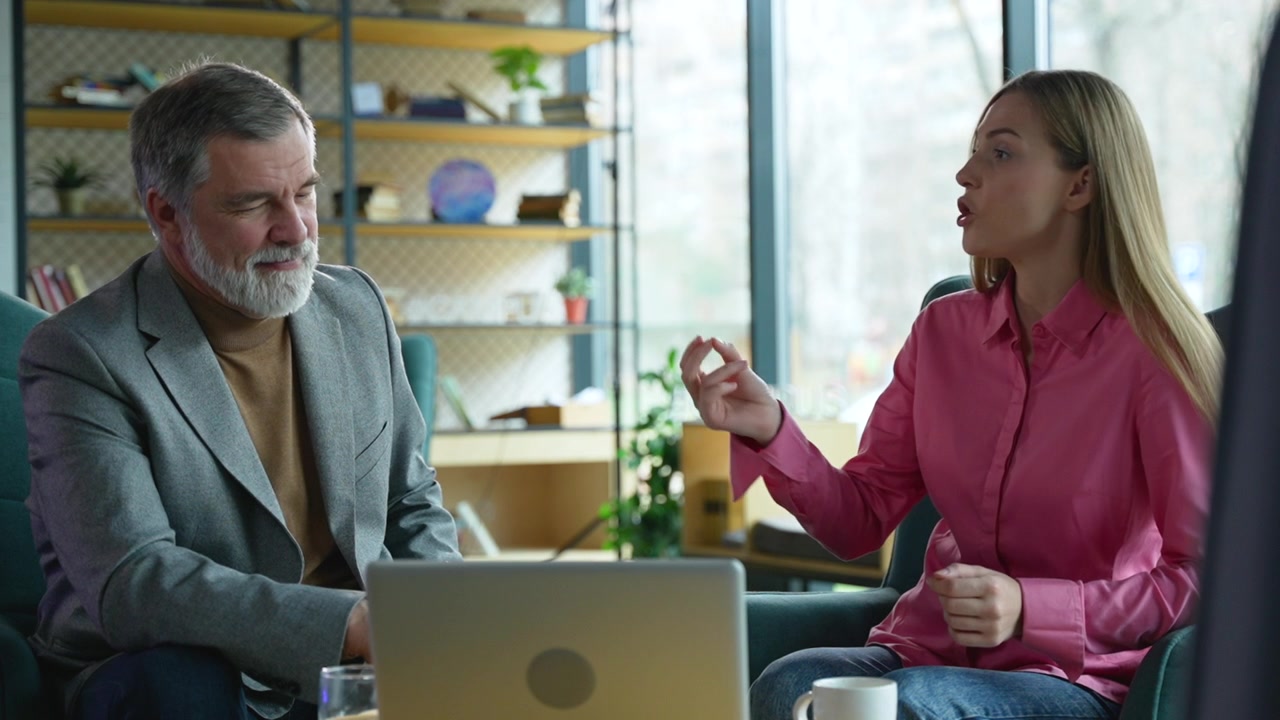 Young Woman Discussing Project with Older Male Colleague in Office