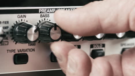 musician's hand sets up the levels of a guitar preamp multi effect, close up