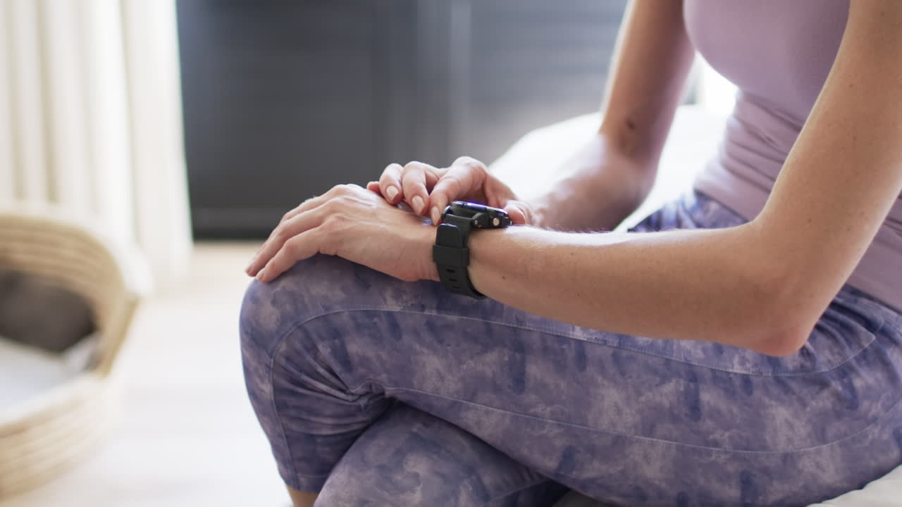 Donna caucasica di mezza età controlla il suo smartwatch a casa, con spazio per il testo
