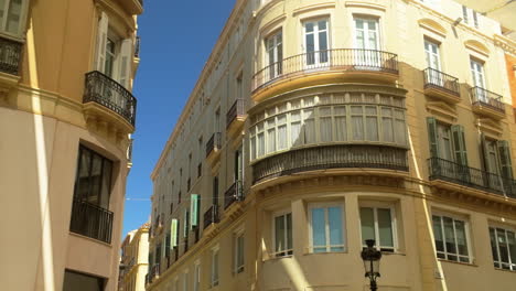 a view of elegant residential buildings in malaga, spain, with curved facades and wrought-iron balconies under a clear blue sky