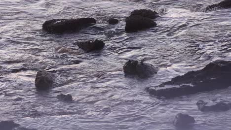 ocean waves breaking on beach rocks on sunny day