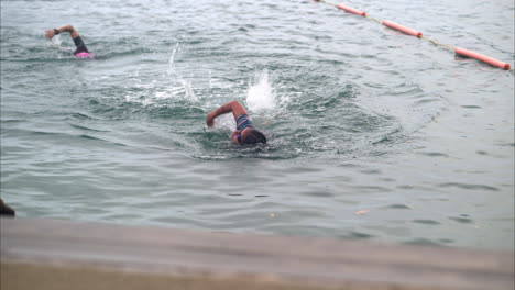 Female-athlete-giving-the-last-stokes-at-the-swimming-stage-of-a-triathlon-competition