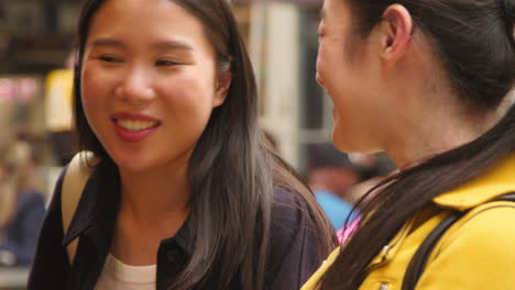 close up of two women buying from street food market stall