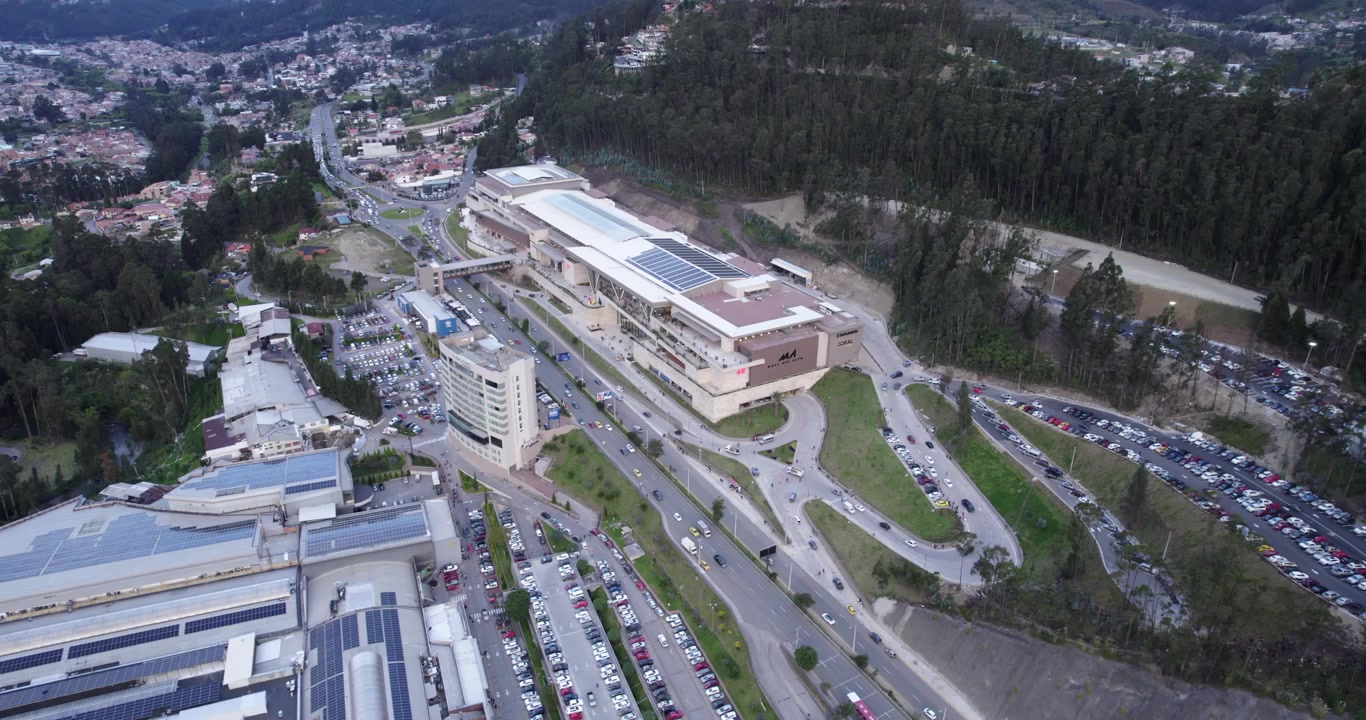Splendida veduta aerea mattutina con drone del centro commerciale Mall del Alto a Cuenca, Ecuador, che rivela il traffico intenso dell'autostrada e il moderno paesaggio urbano in una splendida giornata limpida, inquadratura di apertura