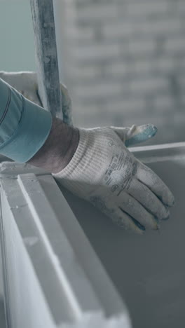 professional repair worker in white gloves holds large measuring ruler and knocks grey construction close view