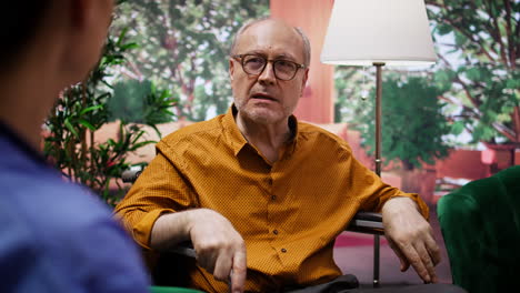 nurse explaining disease diagnosis to elderly man in wheelchair