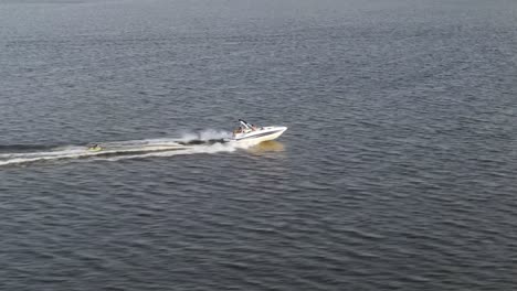 Small-Boat-Being-Towed-Behind-By-A-Speedboat-Across-The-Sea