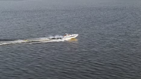 small boat being towed behind by a speedboat across the sea
