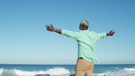 senior man raising his arms at the beach