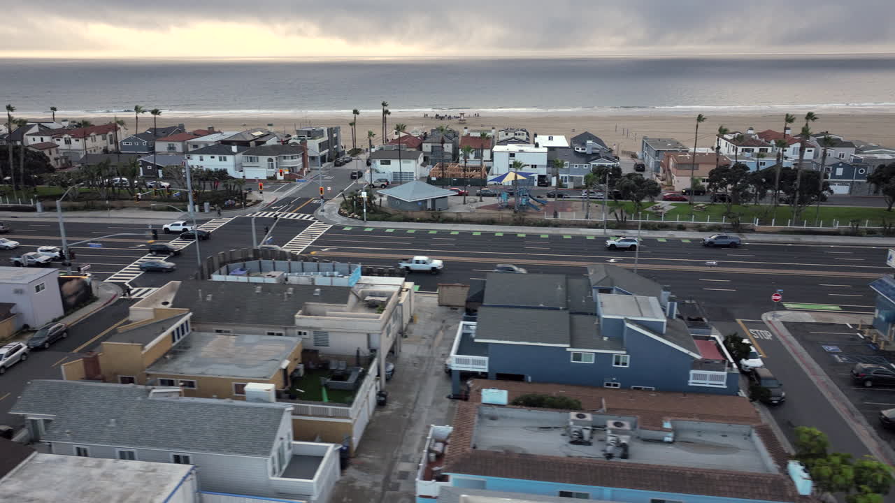Dronebillede af huse ved Newport Beach under en overskyet og regnfuld dag i det sydlige Californien. Kystlinjen virker stille og afdæmpet, hvilket fremhæver boligarkitekturen langs Stillehavet