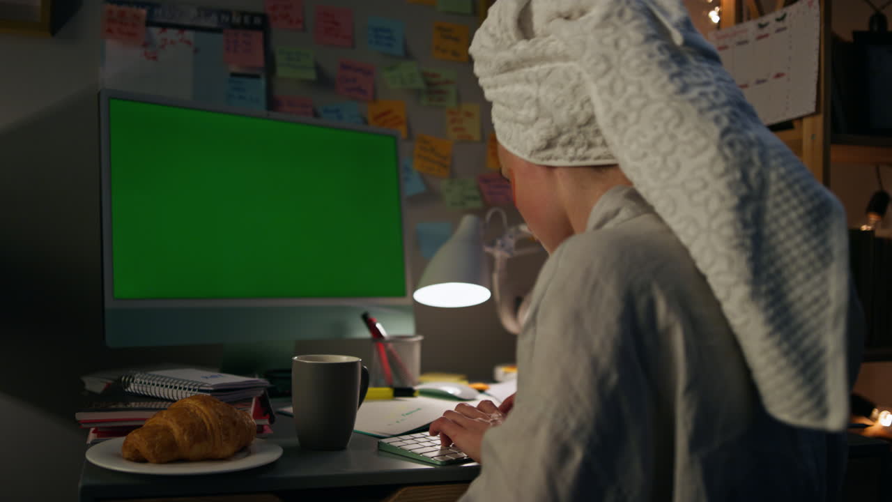 Persona concentrata che digita su un computer con chromakey. Ragazza positiva che chatta con un amico a casa.