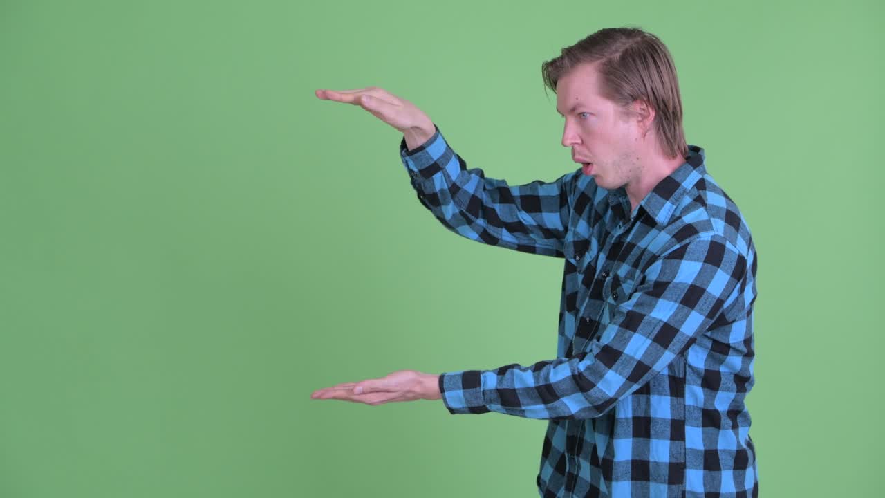 Portrait of Caucasian man showing copy space while looking excited shot against green studio background