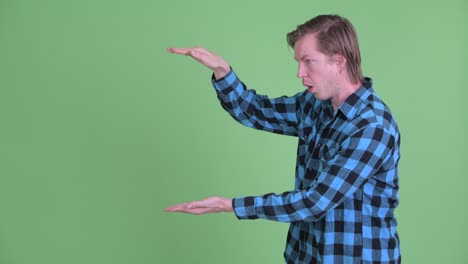 portrait of caucasian man showing copy space while looking excited shot against green studio background