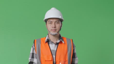 close up of asian male engineer with safety helmet and walking in the green screen background studio