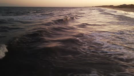 Disparo-Rápido-De-Drones-En-La-Playa-Durante-La-Cálida-Puesta-De-Sol-De-Las-Olas-Rodando