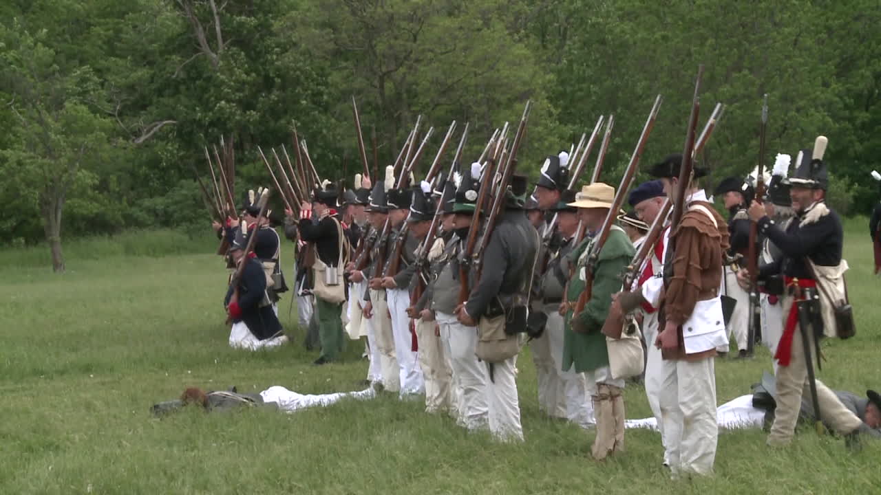 다른 사람들이 1812년 전쟁을 재현한 이 텔레비전 스타일로 싸우는 동안 죽은 사람은 전장에 누워 있습니다.