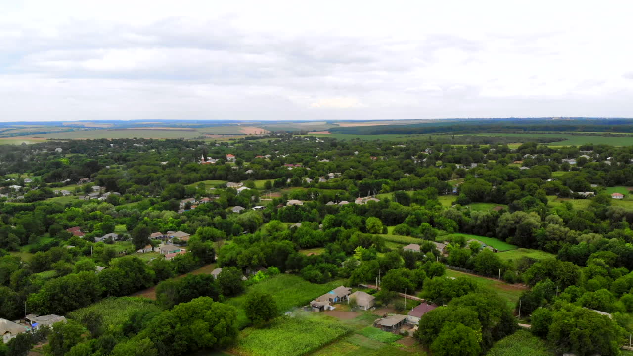Aerial drone shot of Donduseni city with multiple residential buildings and greenery and fields in Moldova