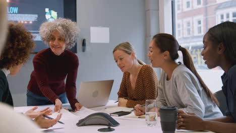 group of businesswomen collaborating in creative meeting around table in modern office