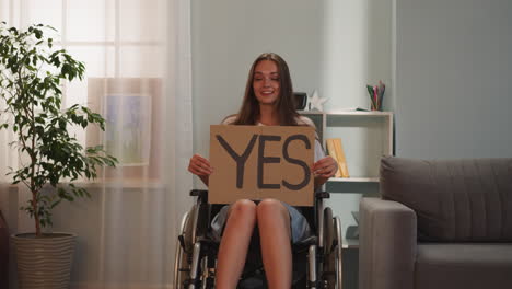 positive brunette woman turns poster with word yes to camera