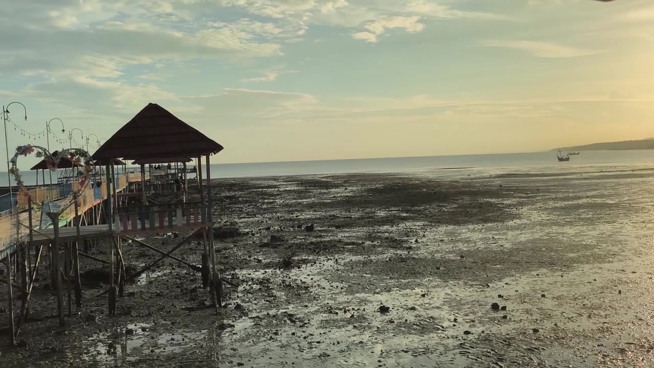 Panoramatický záběr tropické pláže při odlivu s molem během západu slunce