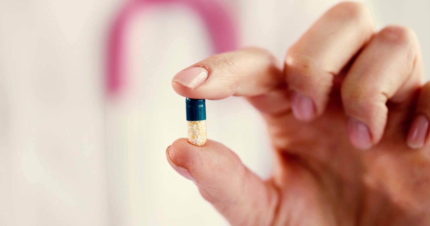 Un primo piano mostra una mano che tiene una capsula, sottolineando l'importanza dell'assistenza sanitaria