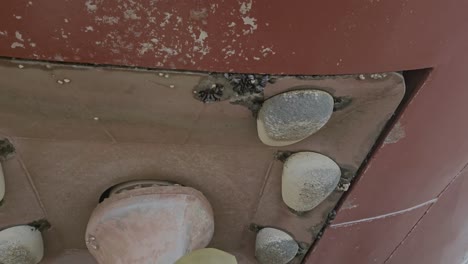 thruster foundation under ship hull in drydock with worn zinc anodes and marine growth. slow panning shot