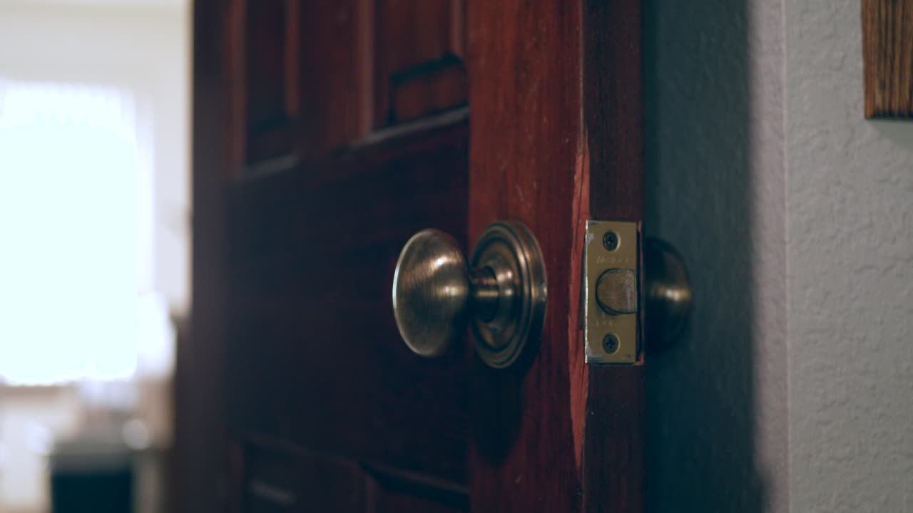 una mano limpiando y desinfectando un pomo de puerta cubierto de gérmenes y virus con un paño antibacteriano desinfectante en un hogar para mantenerse saludable y seguro durante la pandemia