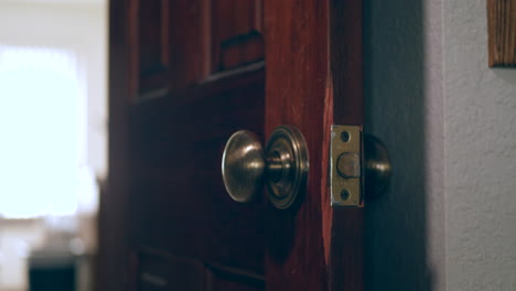 una mano limpiando y desinfectando un pomo de puerta cubierto de gérmenes y virus con un paño antibacteriano desinfectante en un hogar para mantenerse saludable y seguro durante la pandemia