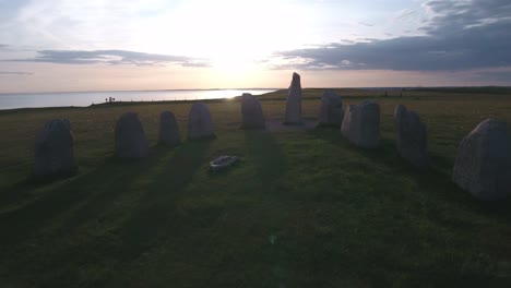 Uralte-Oval-Geformte-Felsen-Ales-Stenar-Am-Abend-Mit-Der-Ostsee-Im-Hintergrund,-In-Südschweden-Skåne-Österlen-Kåseberga,-Luft-Niedrig-Rückwärts