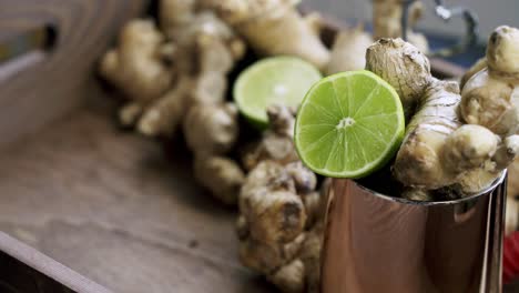 slow zoom in to slice of lime in a cup of ginger with ginger root in the background