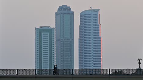 4k:-People-crossing-the-bridge,-city-traffic-and-modern-residential-towers-in-the-background