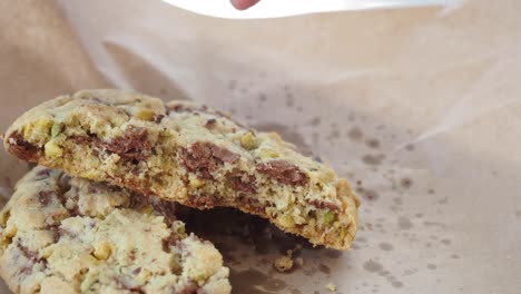 hand holding and breaking a chocolate pistachio cookie