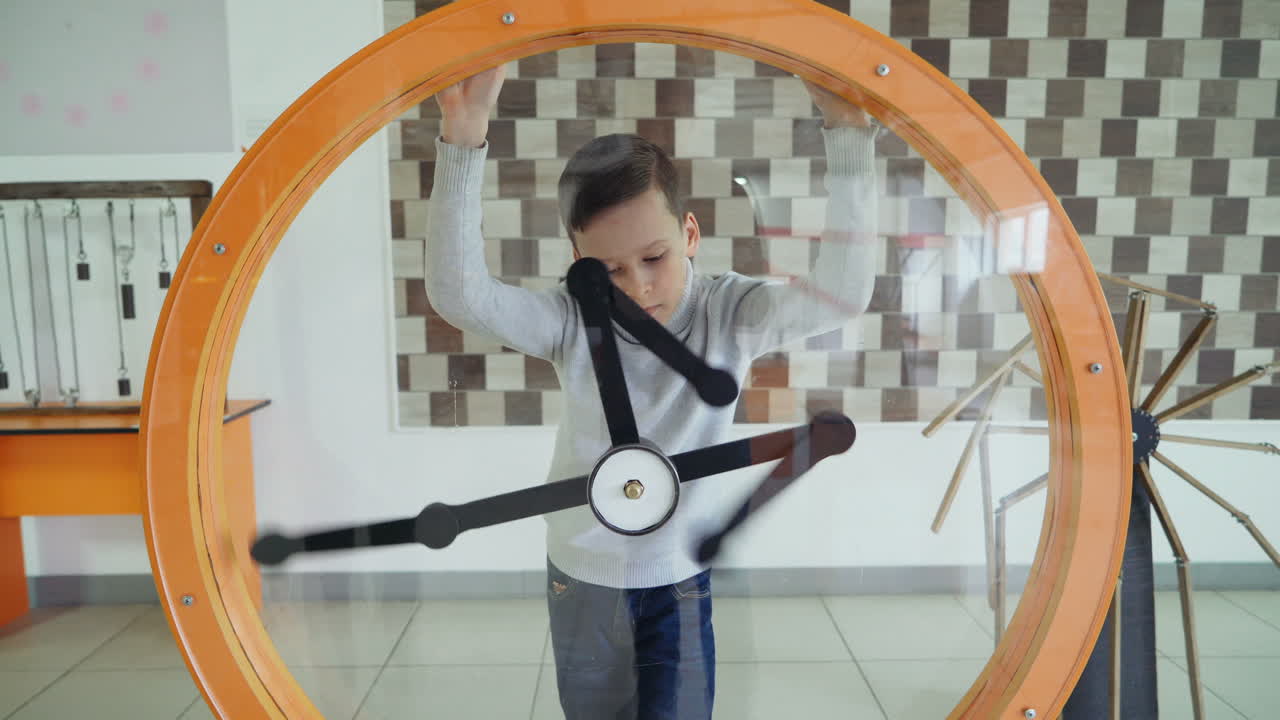 Child views the perpetual motion machine in the children's science museum. Boy in science center.