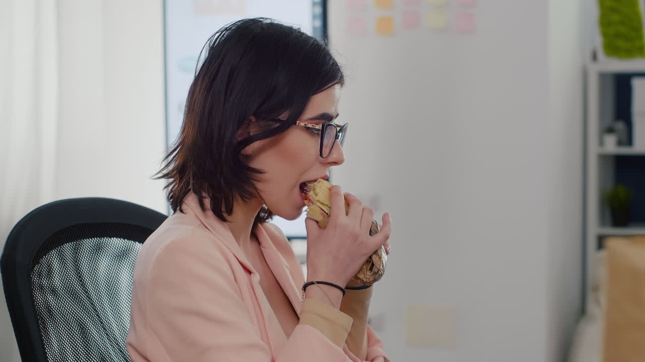 mujer empresaria comiendo un sabroso sándwich teniendo un descanso de trabajo trabajando en una empresa de negocios