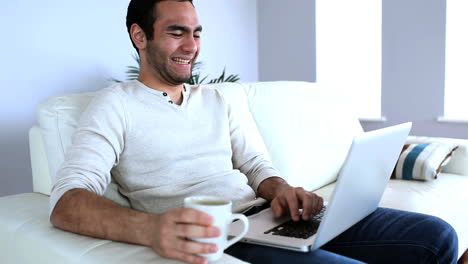 hombre bebiendo un café mientras usa su cuaderno