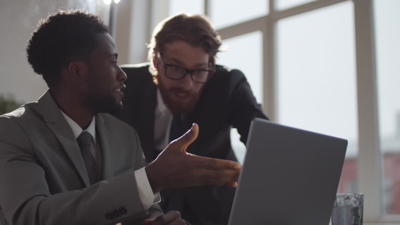 Dois colegas de trabalho diversos usando um laptop e celebrando o sucesso nos negócios.