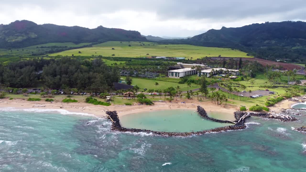 Aerial view of Lydgate Park Pools at Lydgate Beach park near Wailua bay in Kauai with beachfront hotel Hilton Garden Inn Kauai Wailua Bay in background. Holiday in paradise.