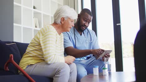 video of african american male doctor using tablet with caucasian senior woman