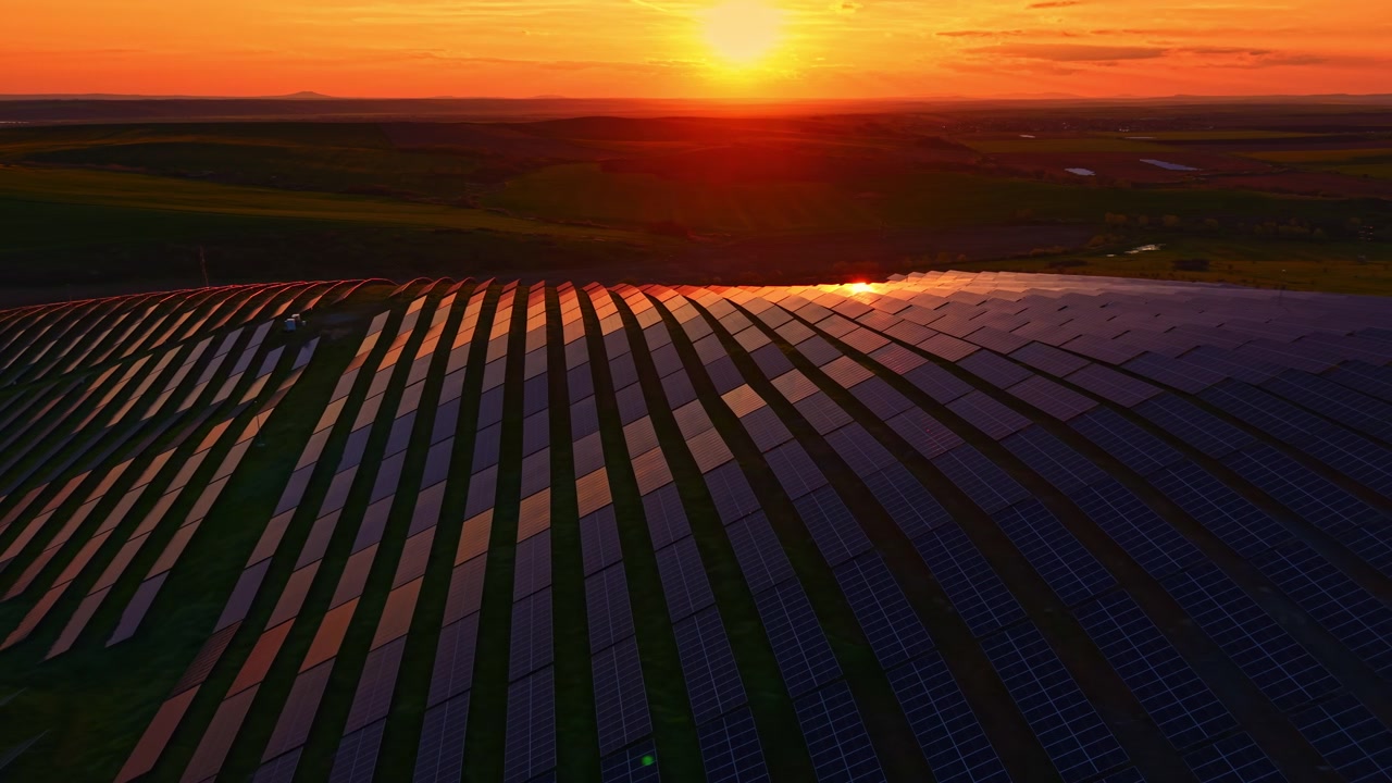 Solnedgang over solpaneler på et vedvarende energifelt beliggende i et landområde.