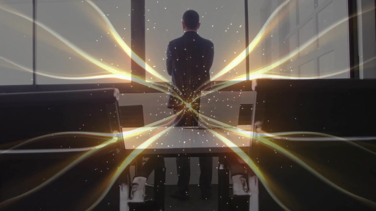 Homem em pé à mesa de conferência em uma reunião de negócios, com rastros de luz dourada irradiando pelas janelas.
