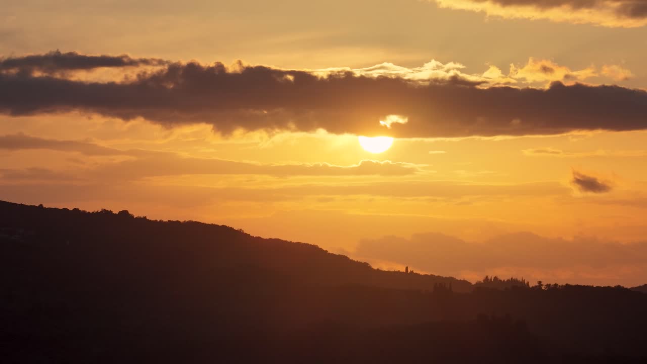 Pôr do sol atrás de uma densa camada de nuvens sobre colinas, paisagem aérea com silhueta durante a hora dourada, cena de natureza tranquila na Grécia, céu romântico ao entardecer com brilho quente