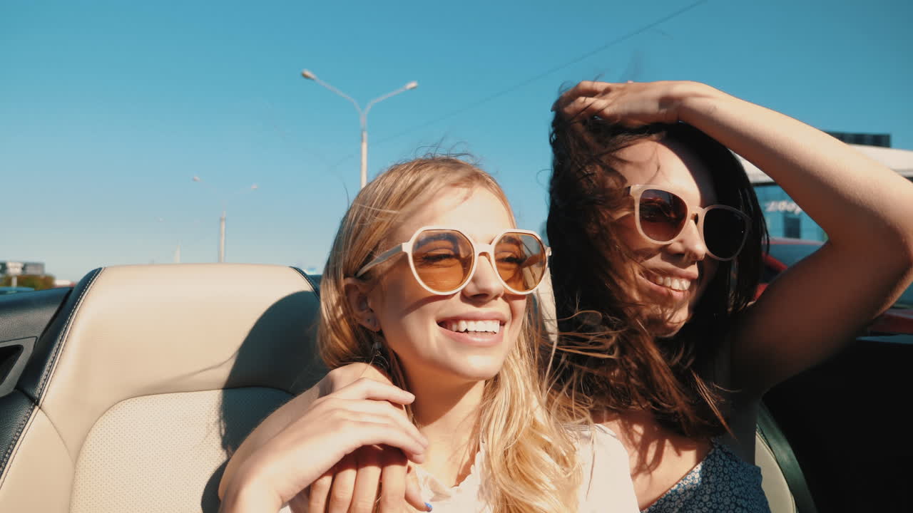 두 명의 행복한 여성들이 컨버터블로 도로 여행을 즐기고 있습니다.