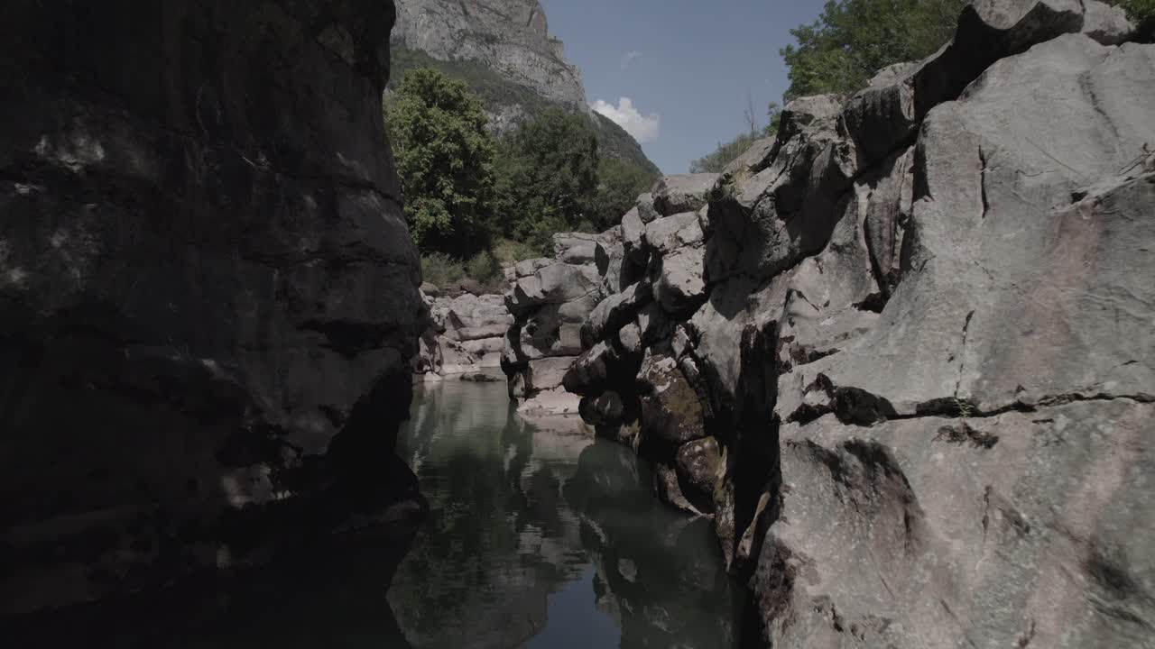 This drone video features a stunning frontal descriptive shot flying over a crystal-clear pool of the Aragón River in the Hecho Valley, nestled in the breathtaking Aragonese Pyrenees, Spain.