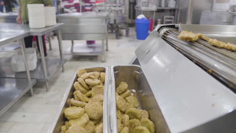 ready meal production line in a factory, a close up view of burger patty are being cooked in a huge fryer